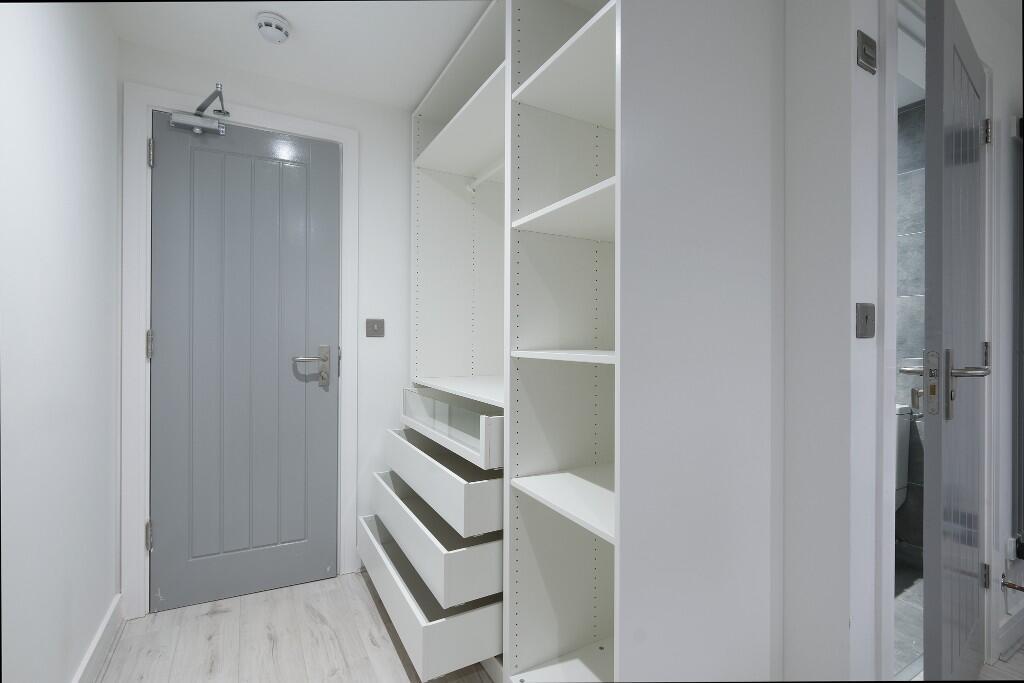 Bright, modern hallway with built-in shelving a...