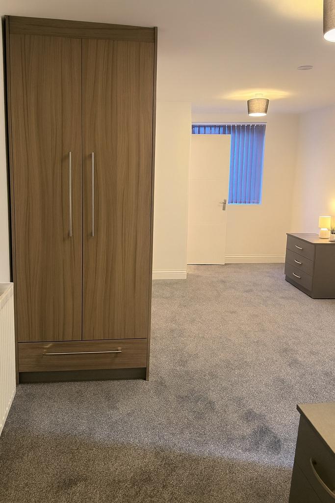 Bright, freshly carpeted bedroom with modern fi...