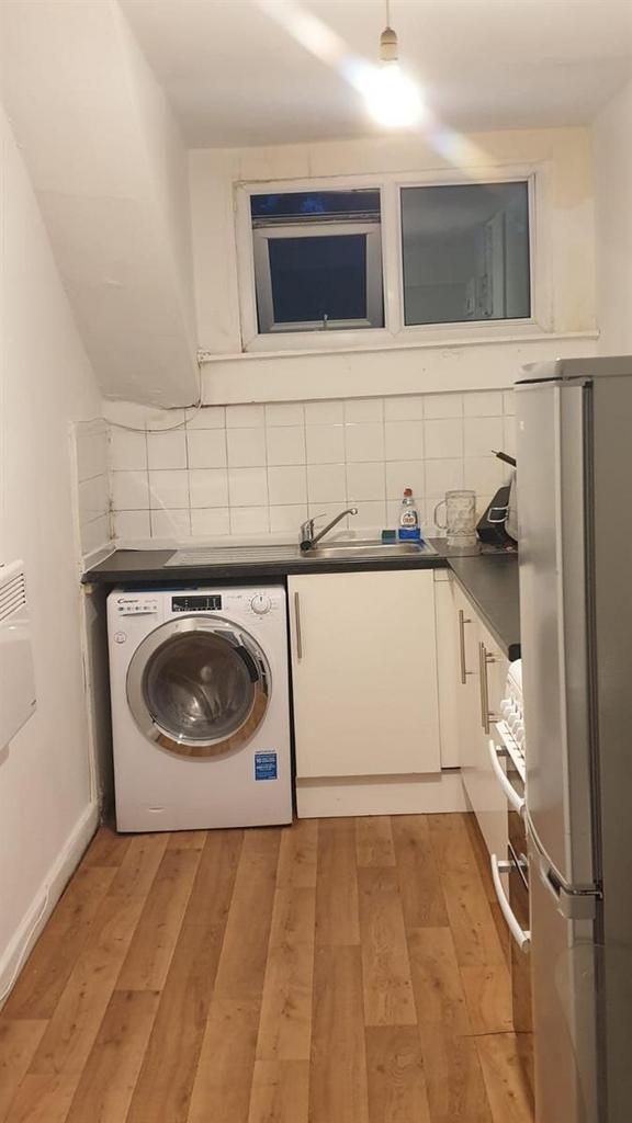 Compact fitted kitchen with wood-effect floorin...