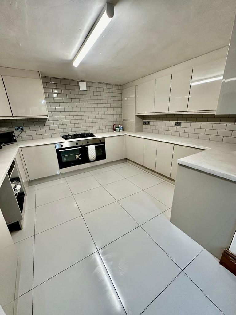 A clean and modern kitchen with ample white cab...