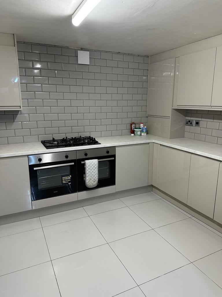 Modern, clean kitchen with white cabinetry, til...