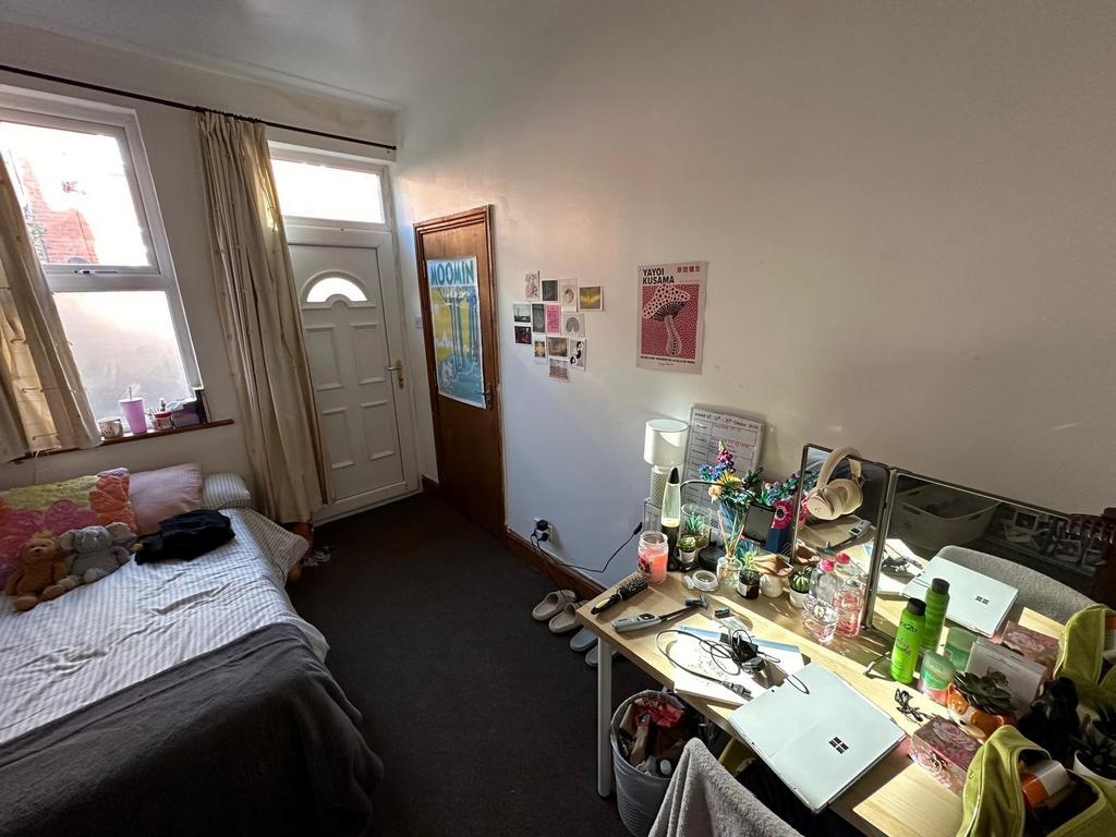 A modest bedroom with a bed, cluttered desk are...