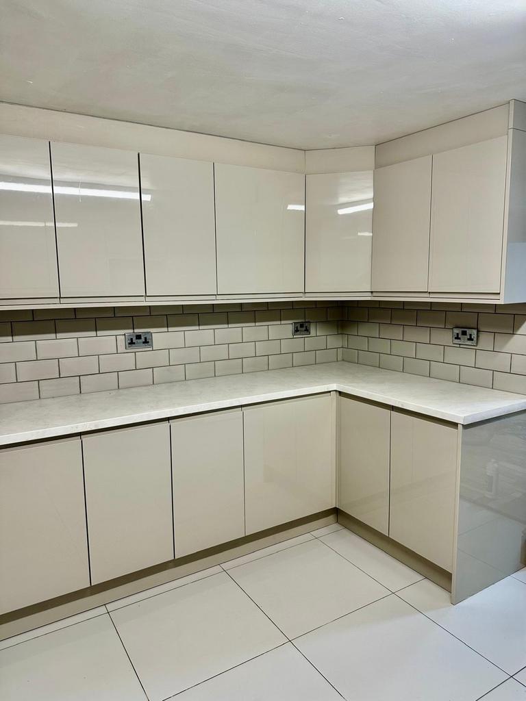 Modern L-shaped kitchen with glossy white cabin...