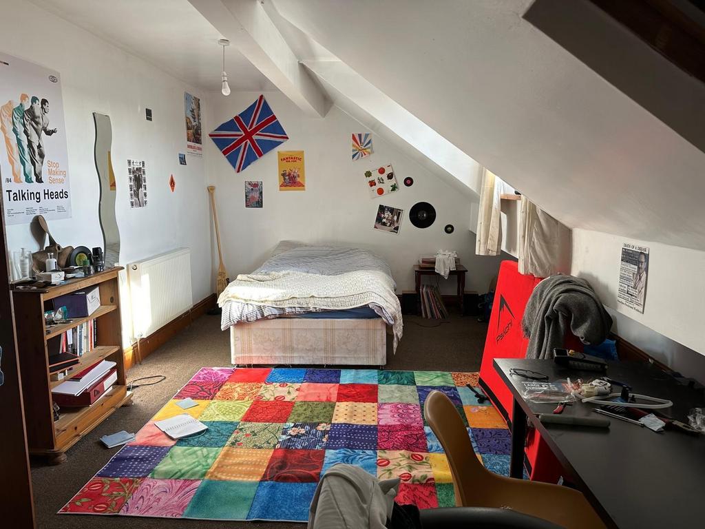 A cozy student bedroom featuring a large bed, c...