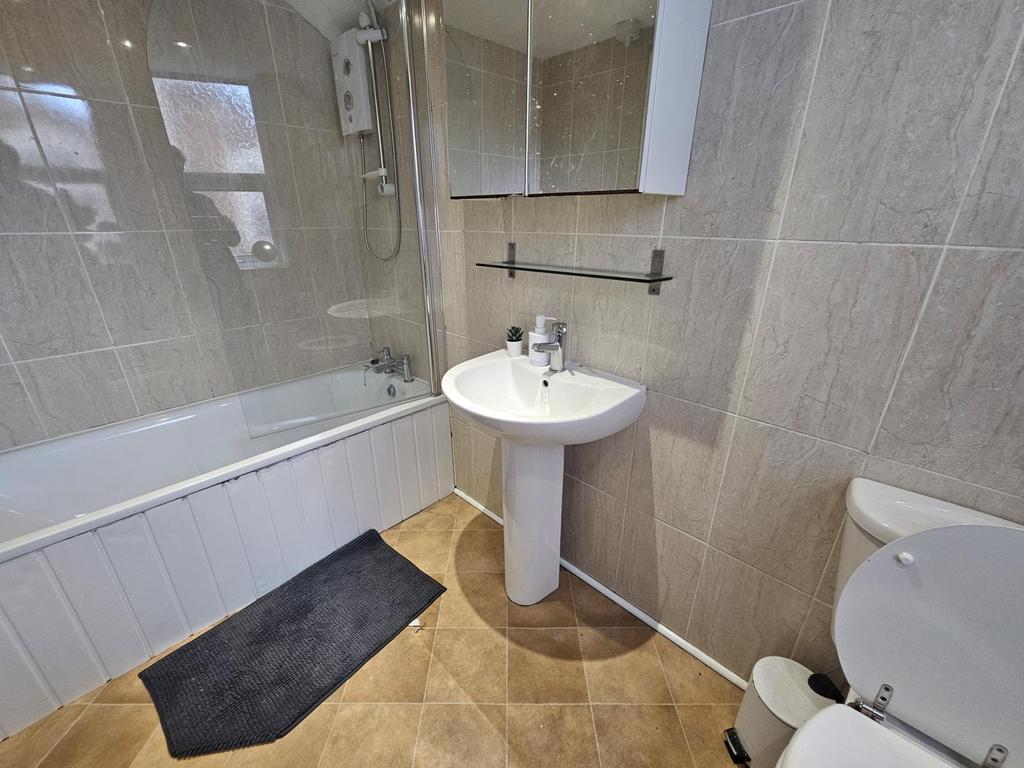 Bright, tiled bathroom with a bath and shower, ...