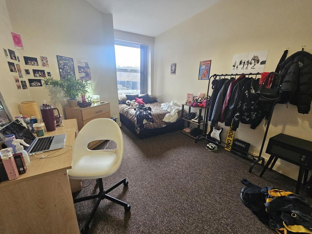 Compact furnished bedroom with a desk, comforta...