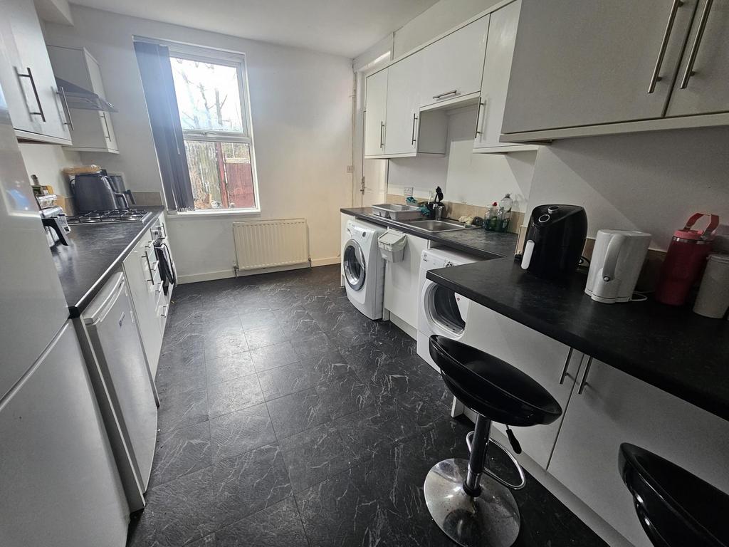 Bright galley-style kitchen with white cabinetr...