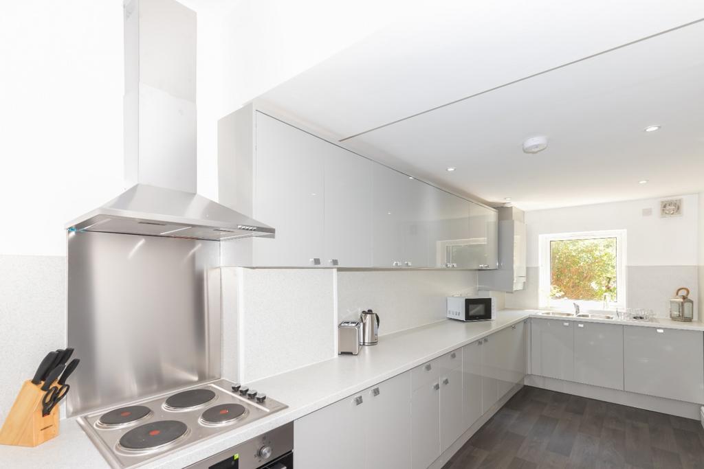 Bright modern galley kitchen with sleek white c...