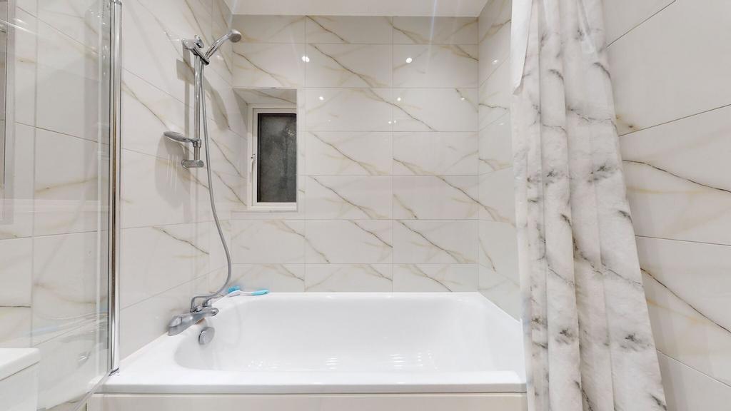 Bright, modern bathroom with a white bathtub, t...