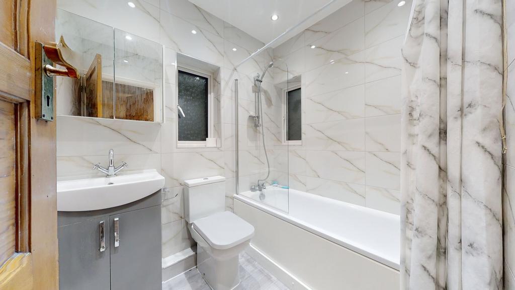 Modern tiled bathroom with a white bathtub and ...