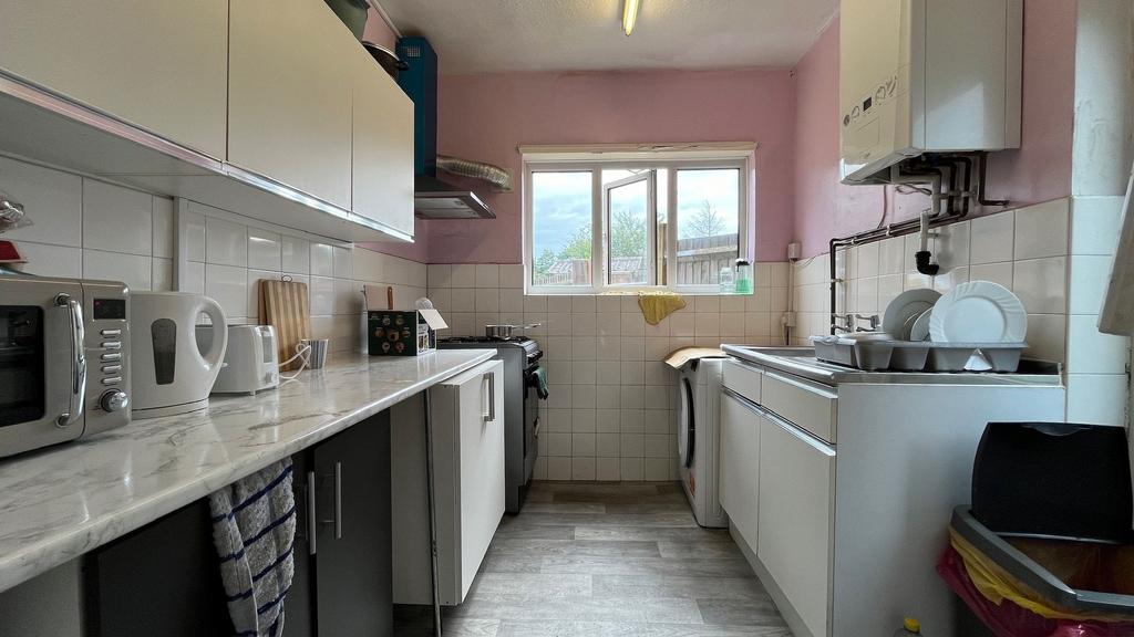 Bright galley kitchen with white cabinetry, lam...