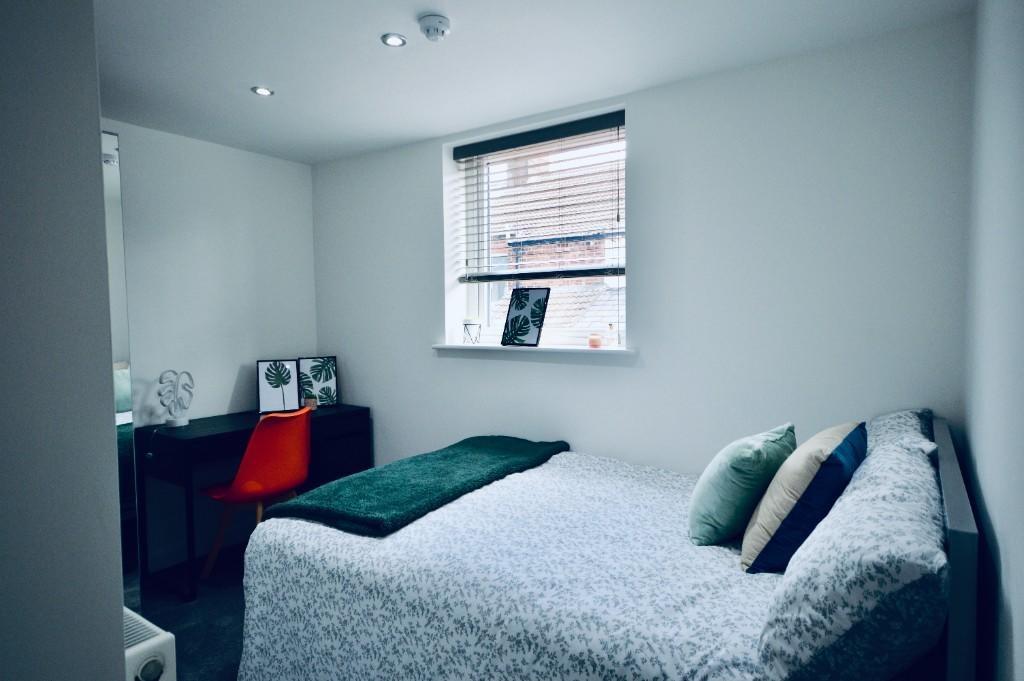 A bright and tidy bedroom with a comfortable be...
