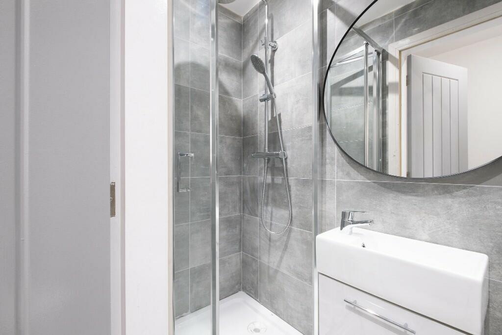 A modern bathroom featuring a sleek shower with...