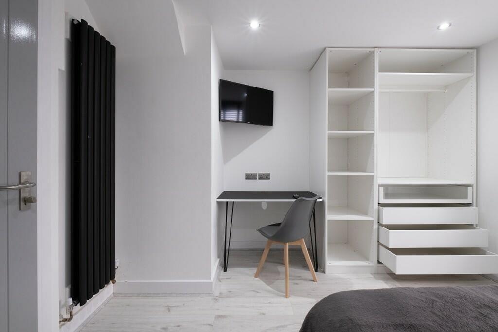 A modern double bedroom featuring a sleek desk ...