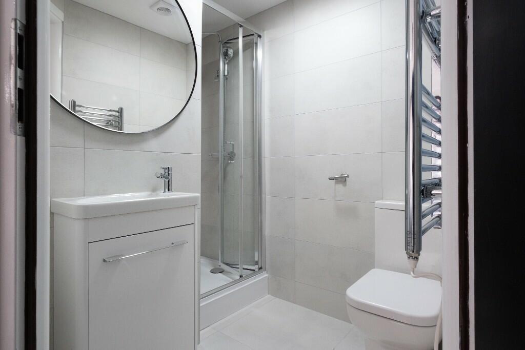 A modern, clean bathroom featuring a shower enc...