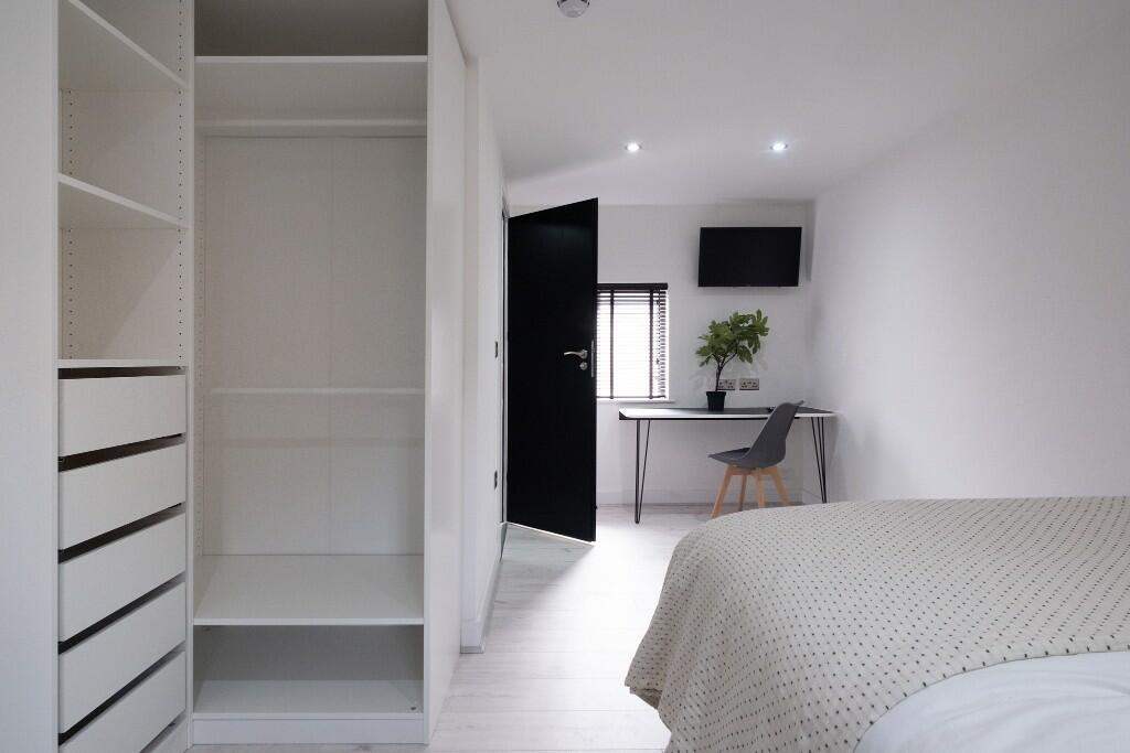 A bright and tidy bedroom featuring a comfortab...