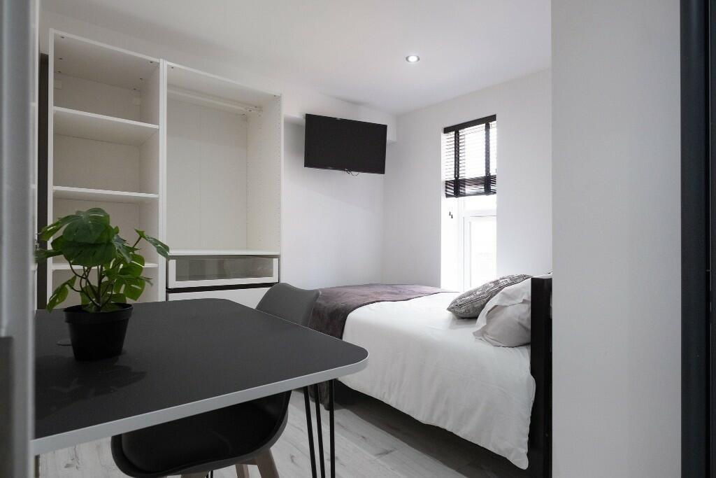 A well-lit, tidy single bedroom featuring a com...