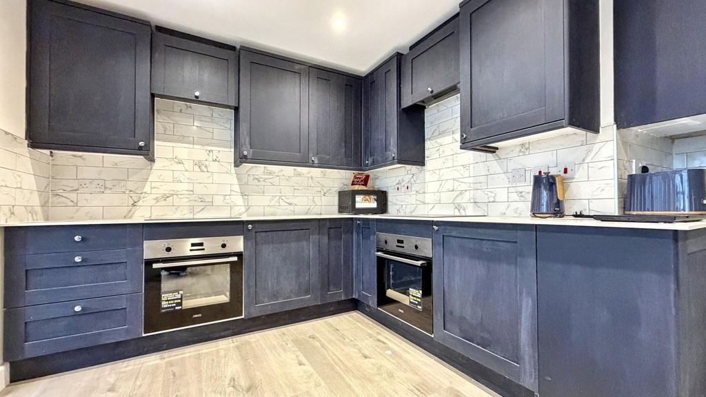 Modern L-shaped kitchen with deep blue cabinetr...
