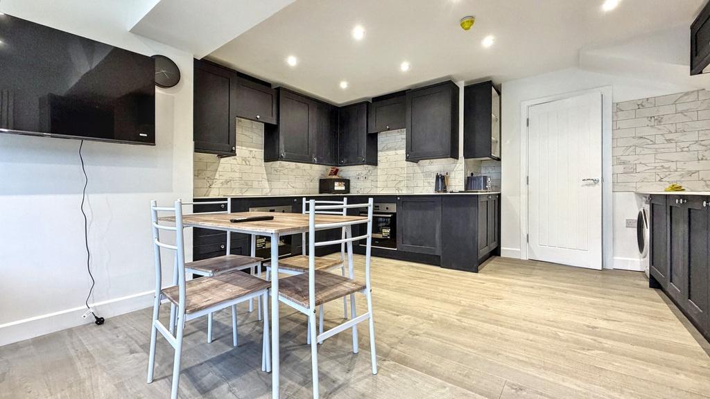 Modern open-plan kitchen with dark cabinetry, i...