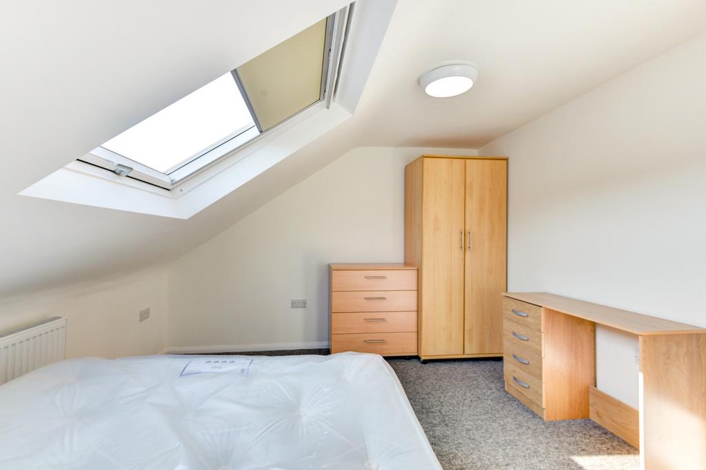 A bright and tidy bedroom featuring a large sky...
