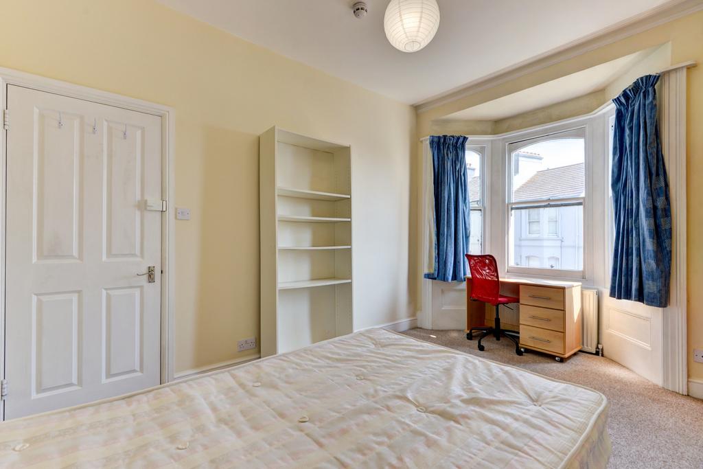 A bright and tidy bedroom featuring a large win...