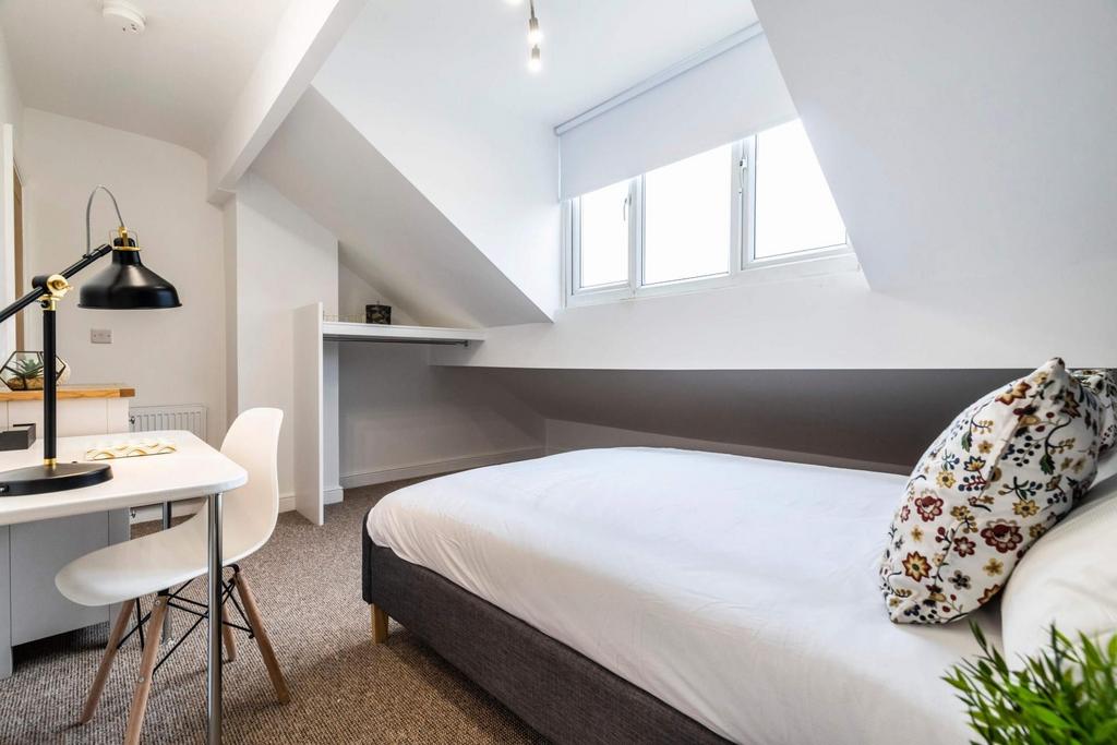 Bright, neatly styled attic bedroom with a comf...