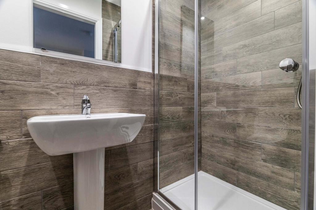 Modern bathroom with tiled walls, a glass-enclo...