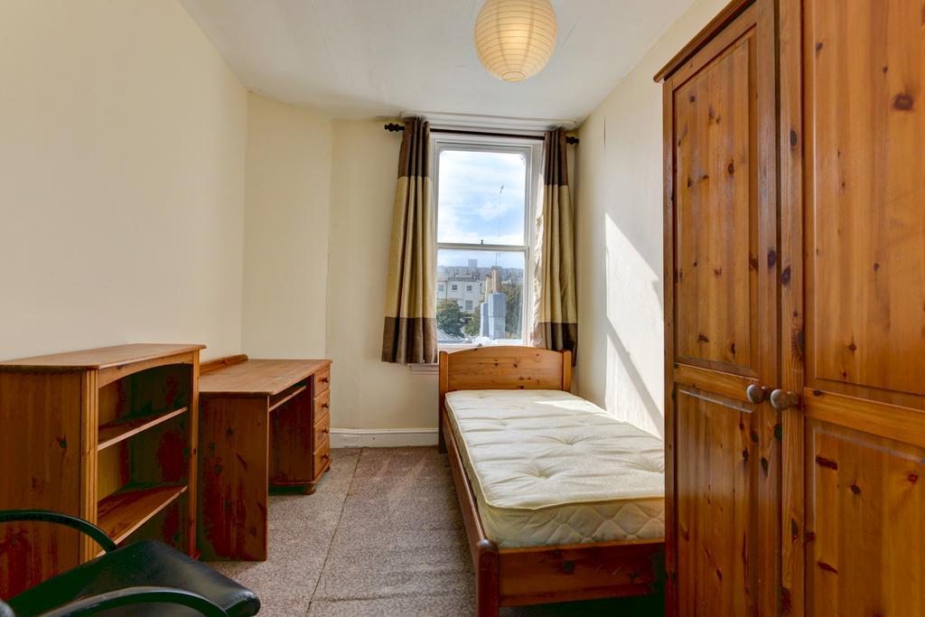 A cozy single bedroom featuring a wooden bed an...