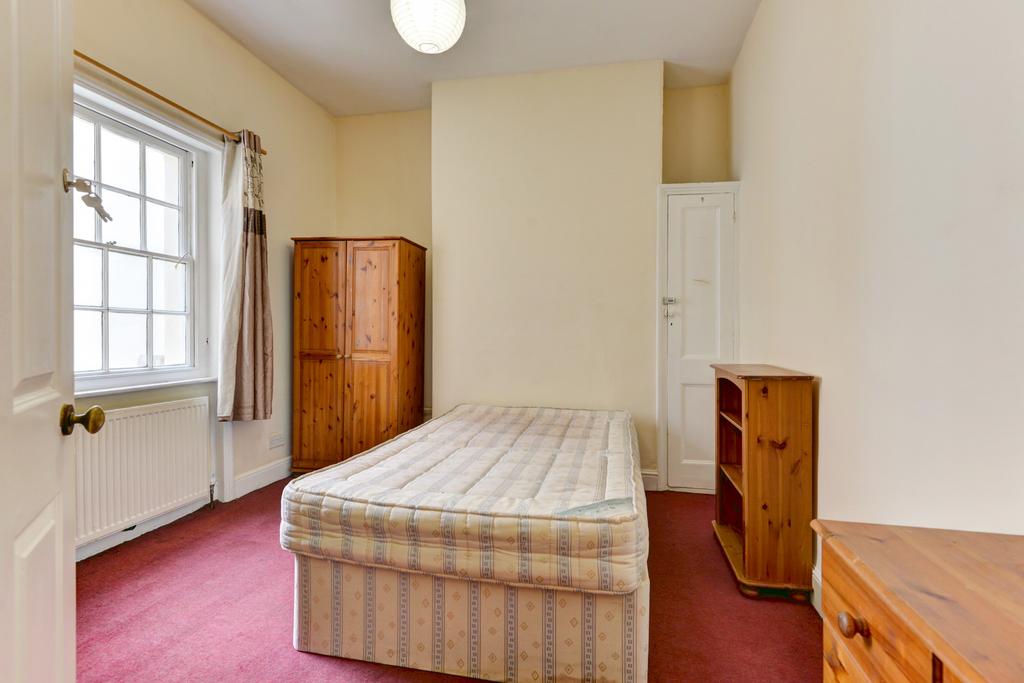 A tidy single bedroom featuring a single bed, w...