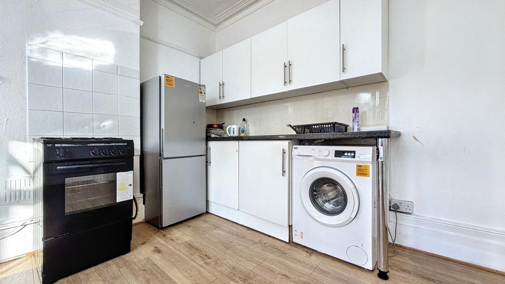 Bright, modern kitchen with white cabinets, lam...