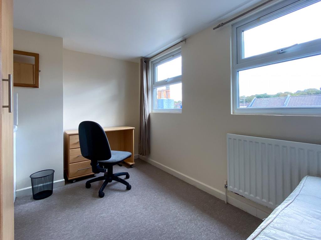 A bright and clean bedroom with two large windo...