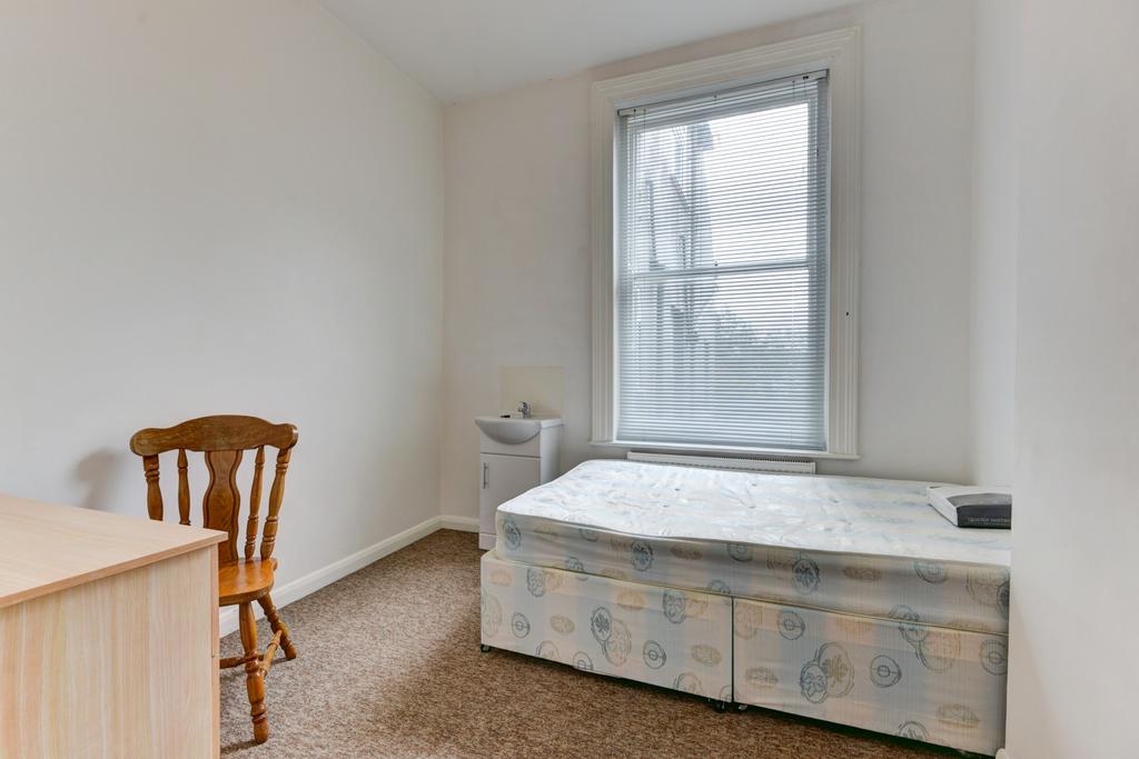 A basic single toilet room with a small window ...