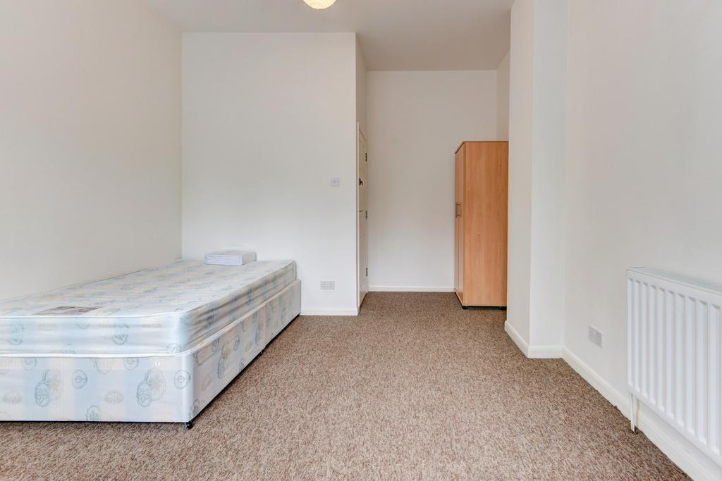 A simple bedroom with a single bed and a small ...