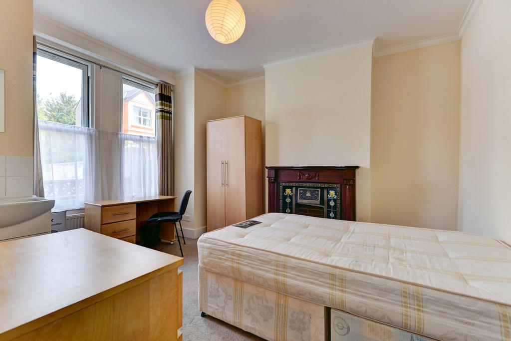 A well-lit and tidy bedroom featuring a comfort...