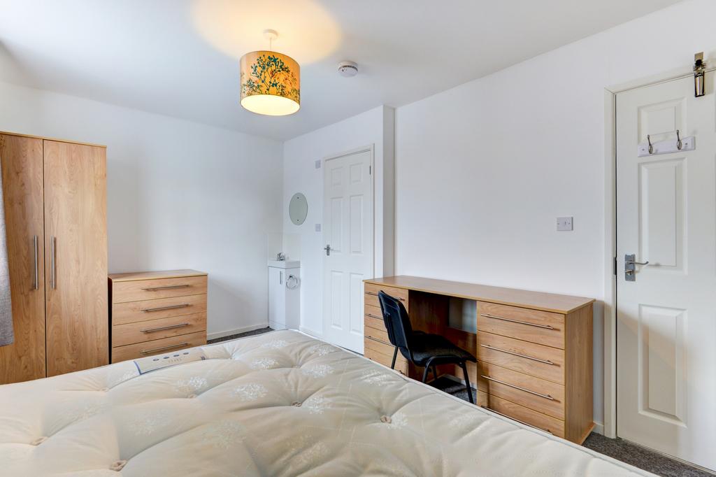 A well-lit, tidy bedroom featuring a comfortabl...