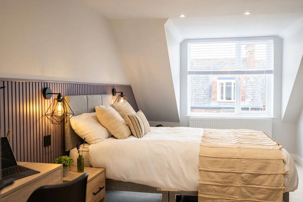 A bright, modern bedroom featuring a neatly mad...