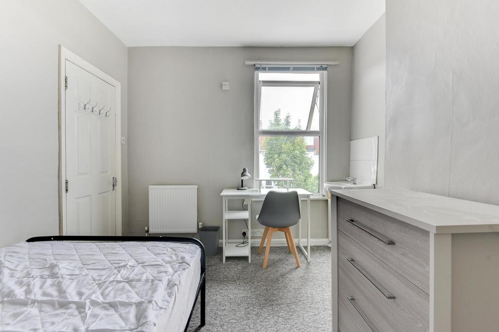 A bright and tidy bedroom featuring a large win...