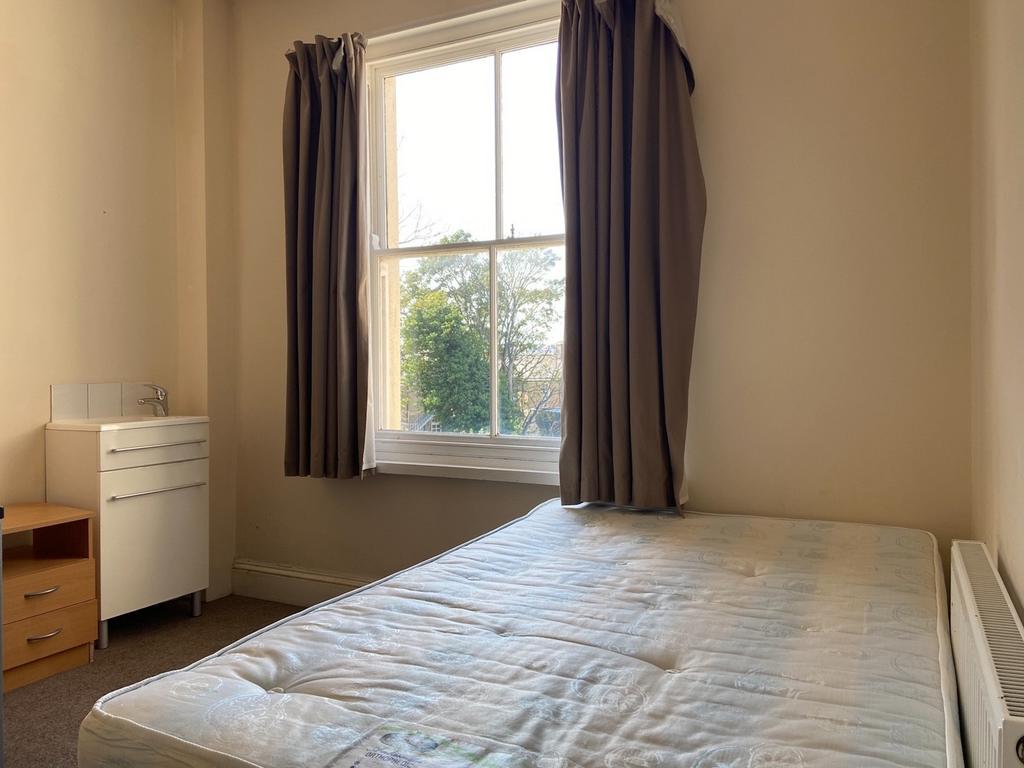 A bright and tidy bedroom with a large window a...