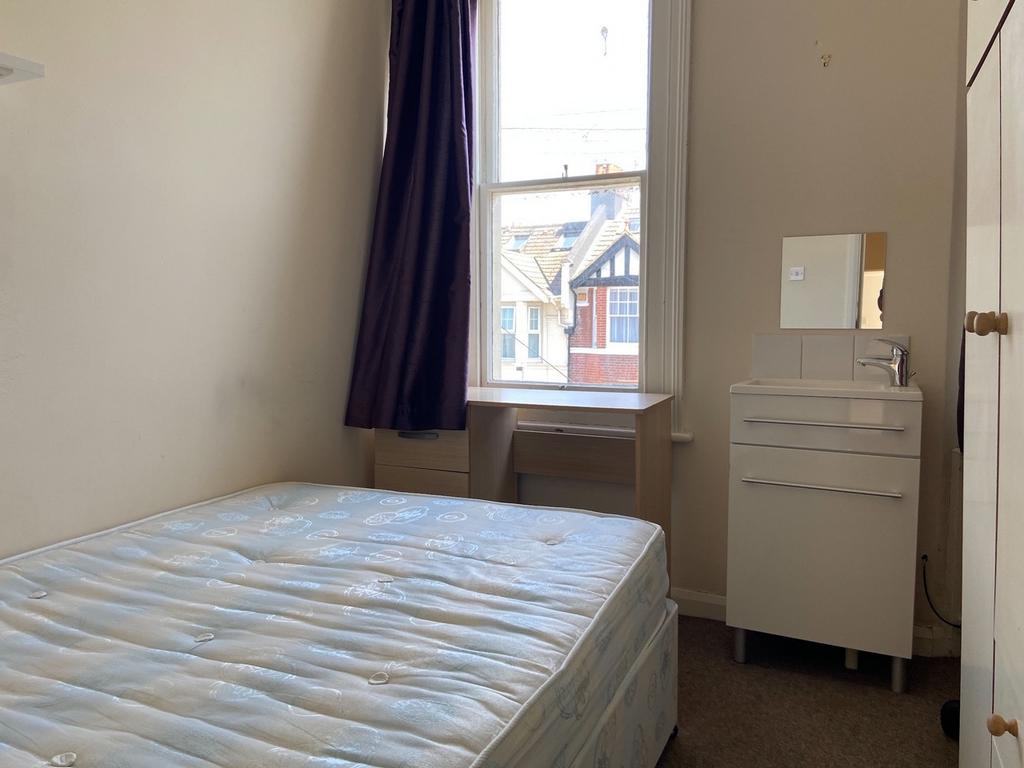 A well-maintained bedroom featuring a large win...