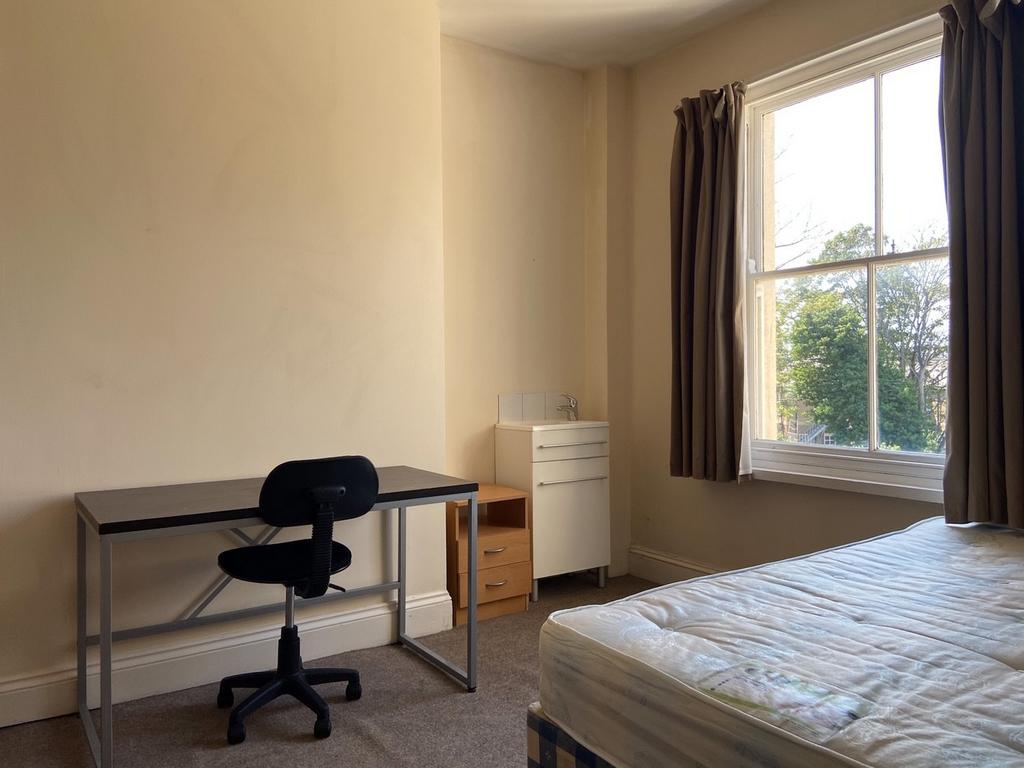 A bright, tidy bedroom with a large window prov...