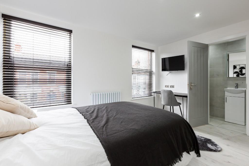 A spacious, well-lit master bedroom with large ...