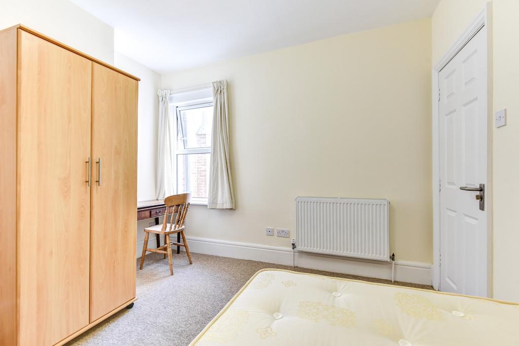 A bright, tidy bedroom featuring a simple woode...
