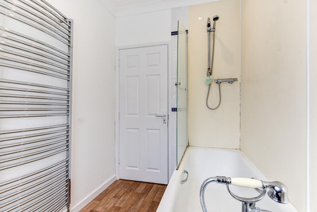 A bright and clean bathroom featuring a bathtub...