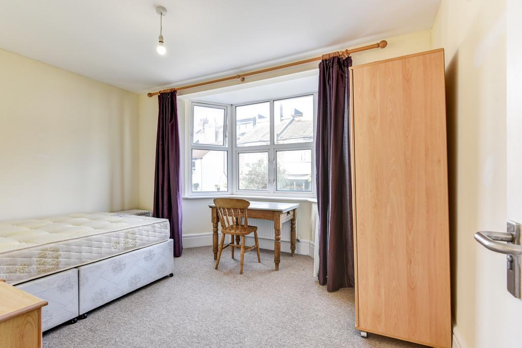 A tidy and bright bedroom featuring a bed, a wi...