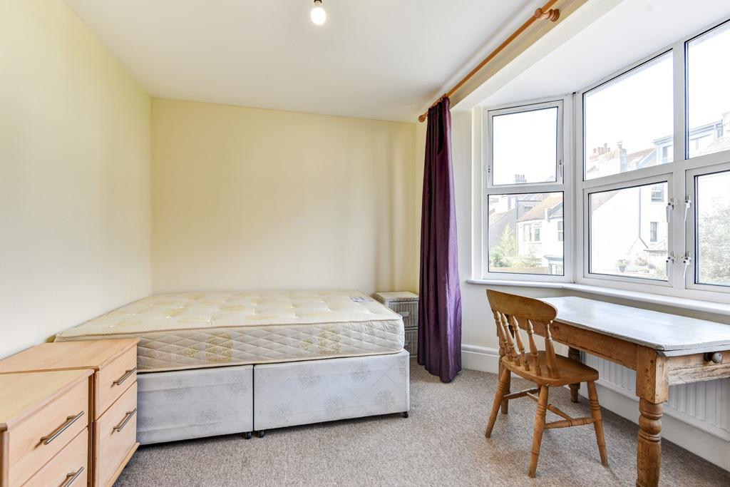 A cozy single bedroom featuring a bed, a desk b...