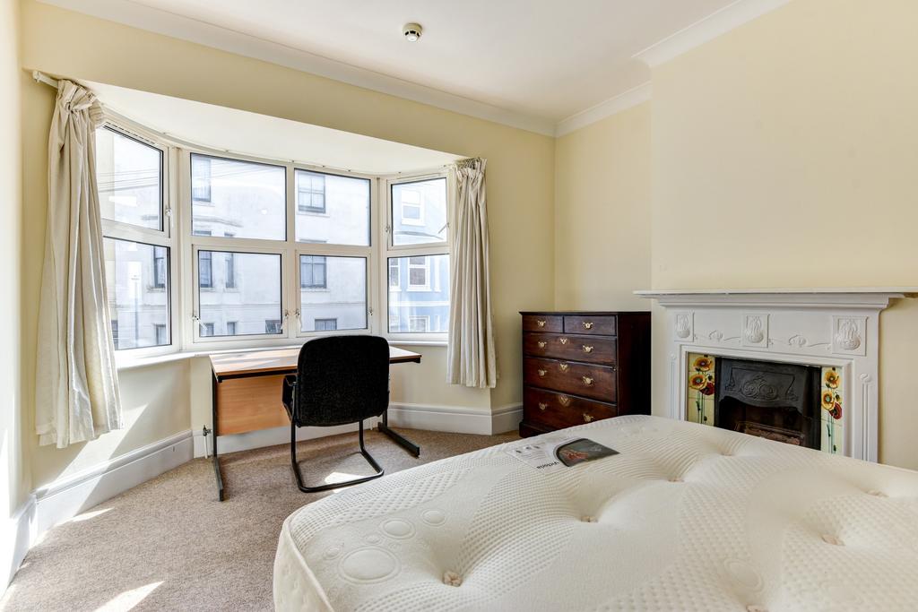 A spacious and well-lit master bedroom with lar...