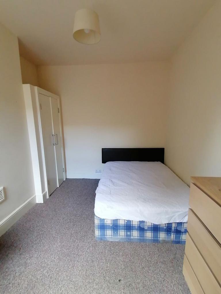 Bright, simply furnished bedroom with a double ...