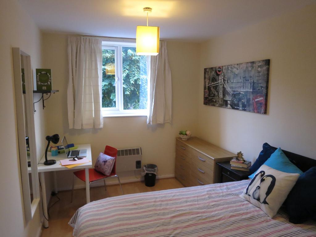 Bright, neatly furnished bedroom with a comfort...