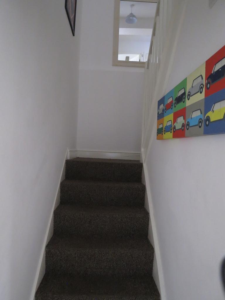 Narrow carpeted staircase with neutral white wa...