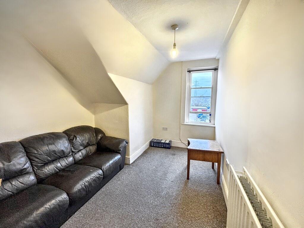 Bright narrow living room with a three-seat lea...